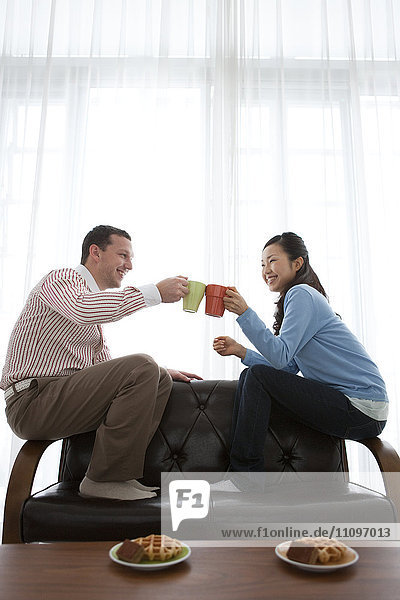Junges Paar stößt mit heißem Getränk an