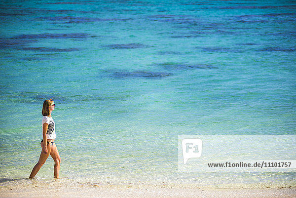 Woman walking along a tropical beach  Rarotonga Island  Cook Islands  South Pacific  Pacific