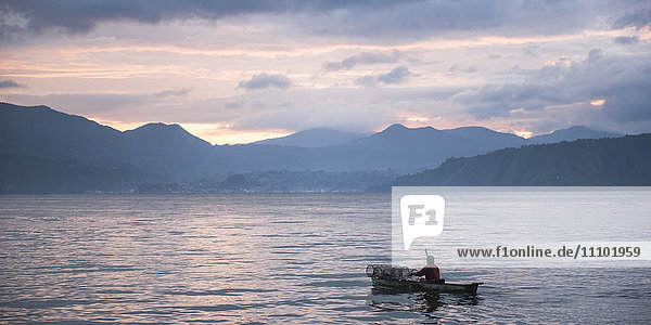 Fischer in einem Fischerboot auf dem Toba-See (Danau Toba) bei Sonnenaufgang  Nordsumatra  Indonesien  Südostasien  Asien