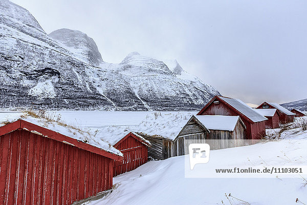 Typische Holzhütten in der verschneiten Landschaft von Lyngseidet  Lyngen Alps  Troms Lapland  Norwegen  Skandinavien  Europa