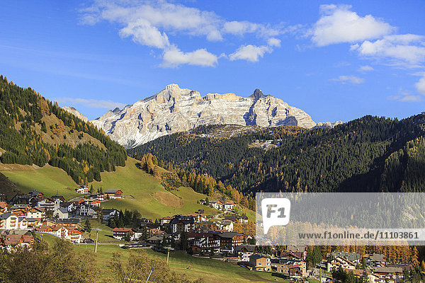 Colourful woods frame the village and the high peaks in autumn  Gardena Pass  South Tyrol  Trentino-Alto Adige  Italy  Europe