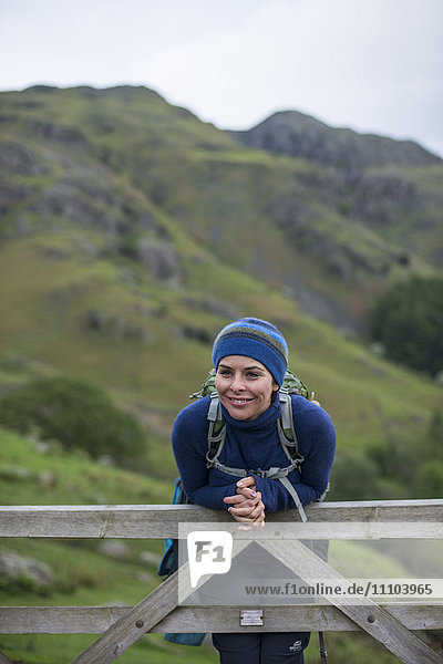 A woman rests on a gate in the Great Langdale valley in The Lake District  Cumbria  England  United Kingdom  Europe