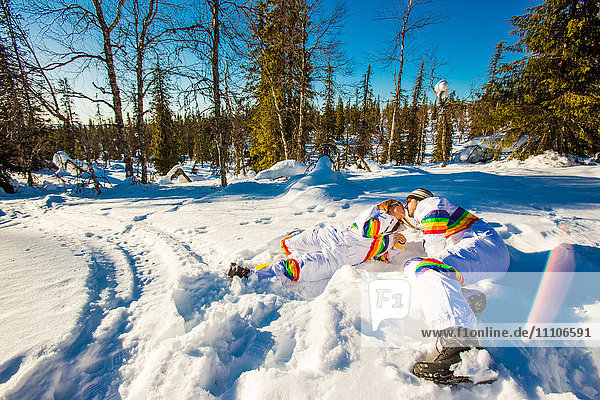 Küssendes Paar in passenden Regenbogen-Skianzügen  Kakslauttanen Igloo West Village  Saariselka  Finnland  Skandinavien  Europa