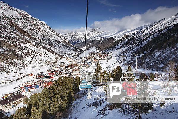 Looking down on the village of Obergurgl sat at the top of the Otztal valley as skiers ascend the mountain on chairlifts  Tyrol  Austrian Alps  Austria  Europe
