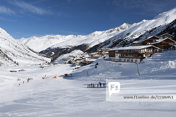 Gruppen von Skifahrern genießen die winterlichen Bedingungen mit dem Dorf Obergurgl und den dahinter liegenden Otztaler Alpen  Tirol  Österreich  Europa