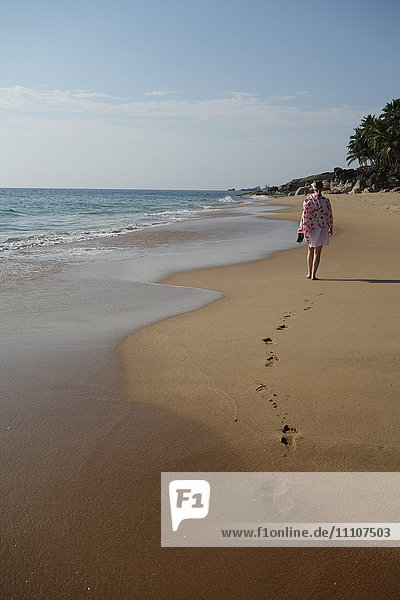 Frau geht und hinterlässt Fußspuren am einsamen Strand  Niraamaya  Kovalam  Kerala  Indien  Asien