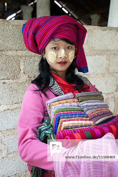 Junges Mädchen mit Thanaka-Paste im Gesicht  das Schals und Sarongs im Nyaung Oak-Kloster  Indein  Inle-See  Shan-Staat  Myanmar (Burma)  Asien  verkauft