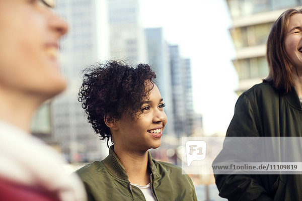 Smiling teenager with short hair standing amidst friends in city