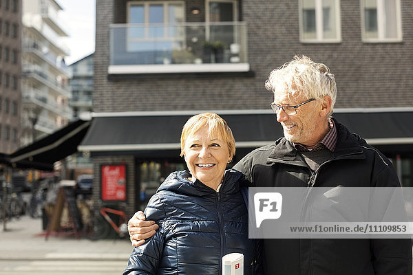Smiling senior couple standing against building