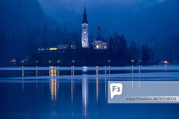 Slowenien  Bleder See und Insel in der Dämmerung: Der See umgibt die Insel Bled mit der Wallfahrtskirche Maria Himmelfahrt