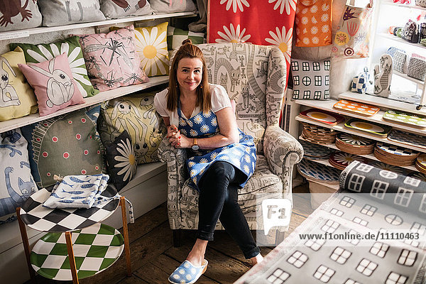 Porträt einer selbstbewussten Besitzerin auf einem Stuhl im Textilgeschäft