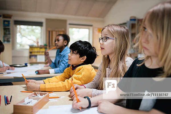 Konzentrierte Schüler sitzen am Schreibtisch im Klassenzimmer