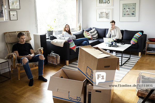 Siblings sitting in living room with cardboard boxes in new home