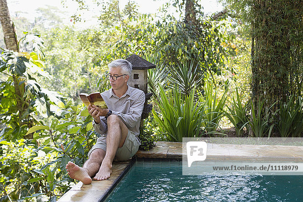 Mann liest Buch am Schwimmbad