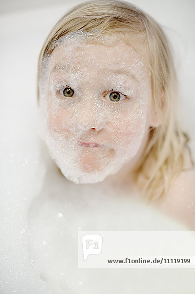 Mädchen spielt mit Blasen in der Badewanne