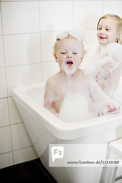 Kinder spielen mit Blasen in der Badewanne