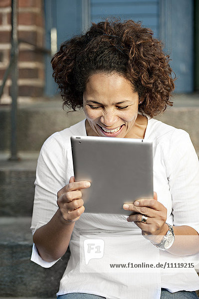Frau hält digitales Tablet  lachend