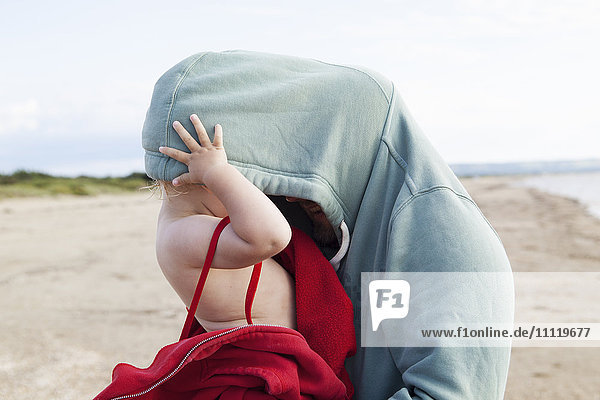 Schweden  Halland  Mellbystrand  Girl (2-3) versteckt in father´s Kapuzenshirt