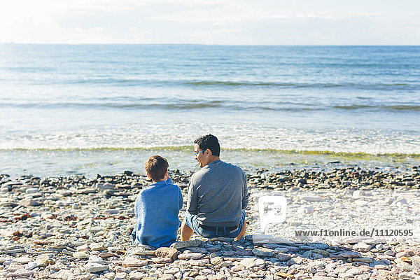 Schweden  Oland  Kopingsvik  Vater und Sohn (8-9) am Strand sitzend