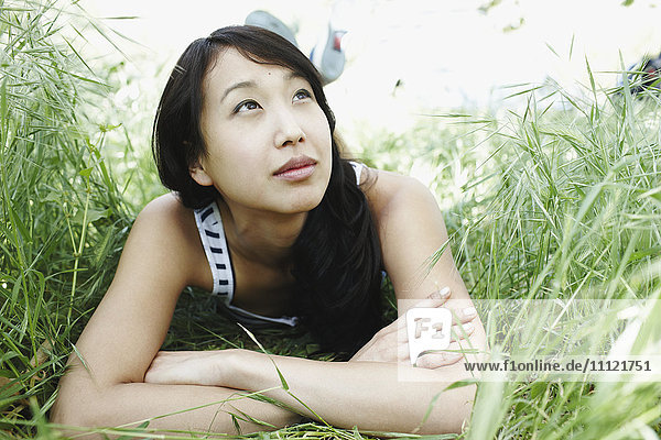 Asiatische Frau liegt im Gras