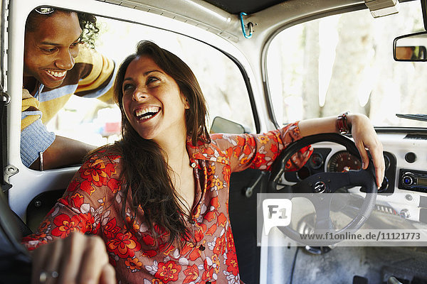 Hispanische Frau sitzt im Auto und lacht über ihren Freund
