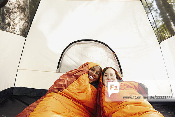 Multiethnisches Paar in Schlafsäcken und Zelt
