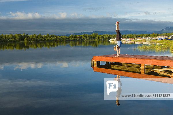 Kaukasische Frau übt Yoga auf einem Steg am stillen See  Anchorage  Alaska  Vereinigte Staaten