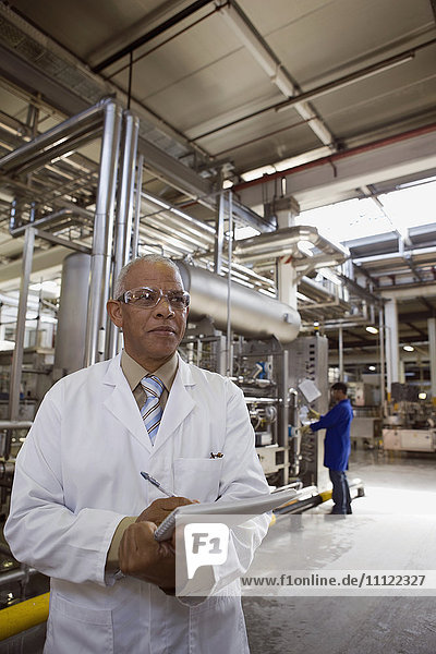 African scientist standing in factory with clipboard