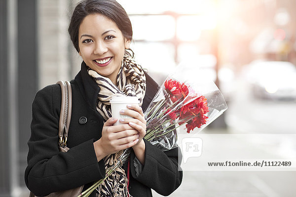 Gemischtrassige Frau mit Kaffee und Blumenstrauß