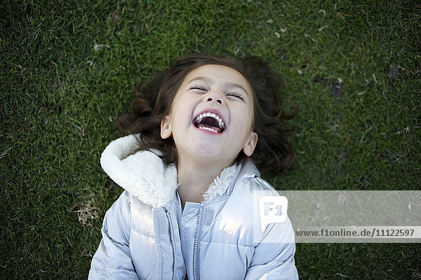 Laughing mixed race girl laying in grass