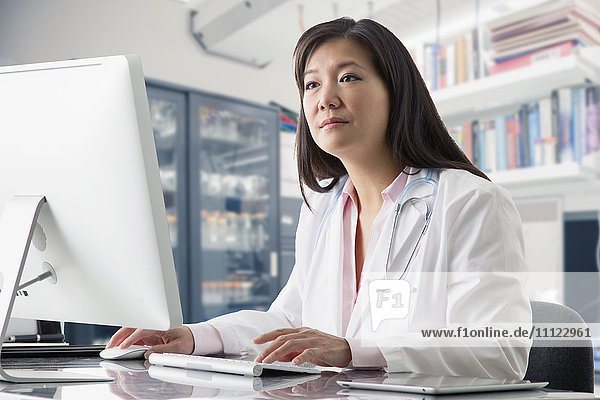 Asiatischer Arzt arbeitet am Computer im Krankenhaus