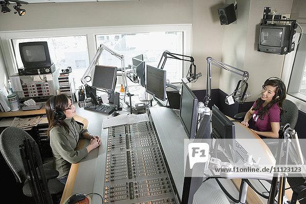 Asiatischer DJ bei einem Radiosender mit Mitarbeiterin