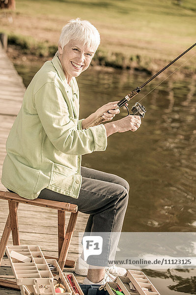 Older Caucasian woman fishing in rural lake