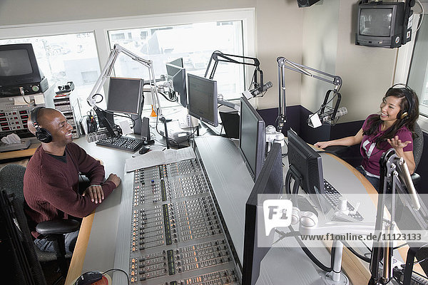 Asiatischer DJ bei einem Radiosender mit Mitarbeiterin