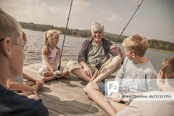 Older Caucasian man teaching grandchildren to fish