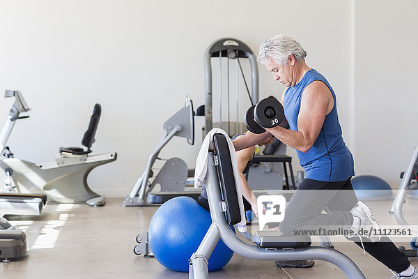 Älterer hispanischer Mann hebt Gewichte im Fitnessstudio