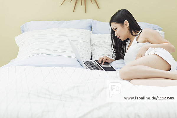 Vietnamese woman using laptop in bed