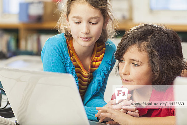 Caucasian children using laptop in library