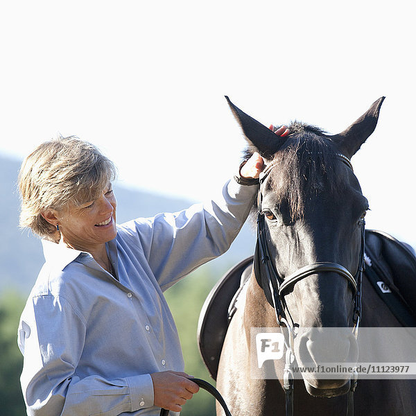 Kaukasische Frau streichelt Pferd