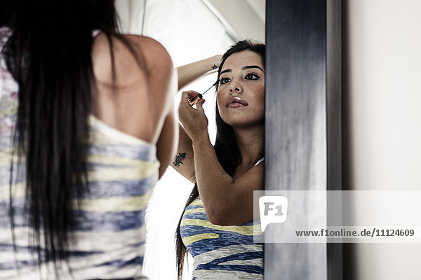 Frau trägt Make-up im Spiegel auf