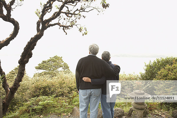 Älteres Paar steht Arm in Arm im Freien