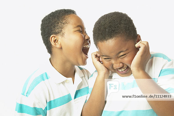 Junger afrikanischer Junge schreit seinem Zwillingsbruder ins Ohr