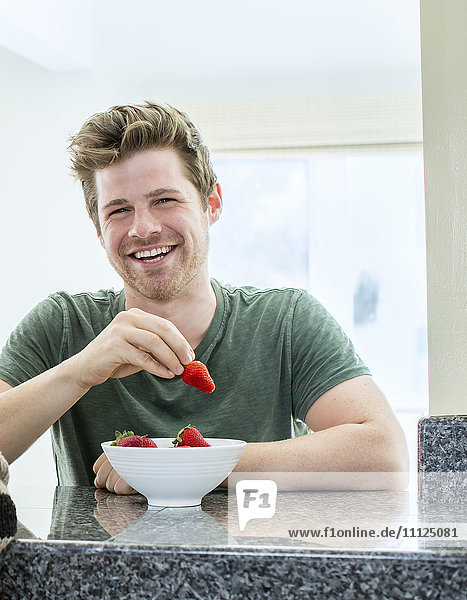 Man eating strawberries in kitchen