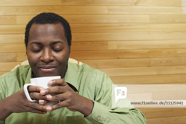 Afrikanischer Mann riecht an einer Tasse Kaffee