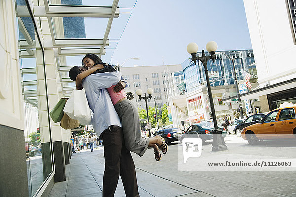 African hugging on sidewalk