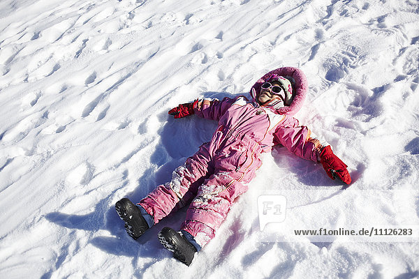 Mixed race girl making snow angels