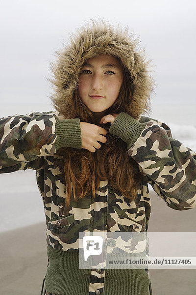 Mixed Race Mädchen trägt Jacke am Strand