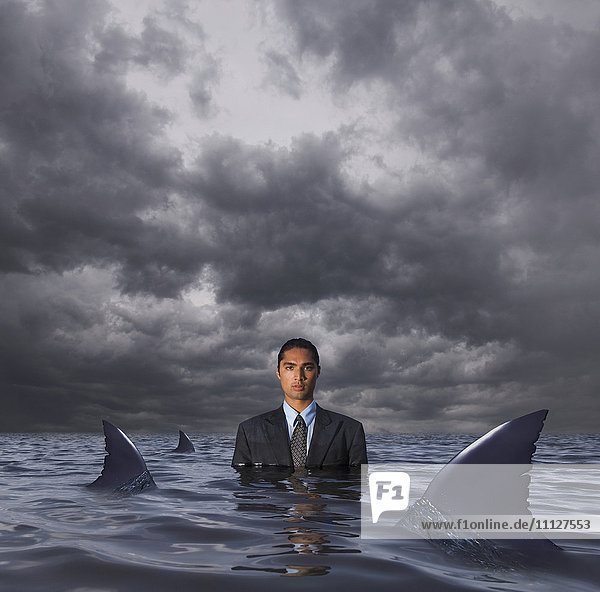 Hispanischer Geschäftsmann steht im Wasser mit Haien