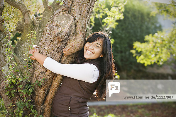 Hispanische Frau  die einen Baum umarmt