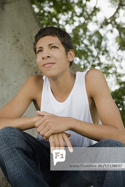Hispanic teenage boy sitting outdoors